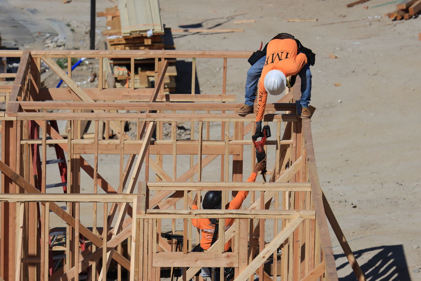 Dos carpinteros pasando una herramienta mientras construyen la estructura de madera de una casa